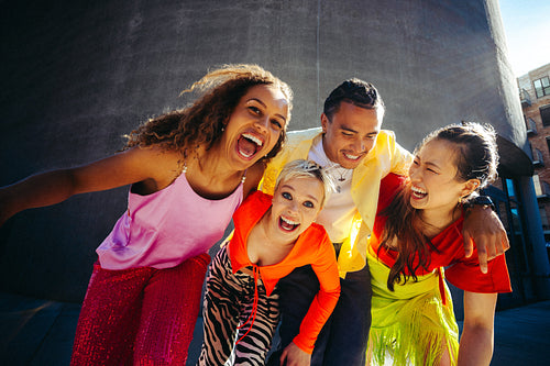 Playful friends lean together for a group portrait outdoors in the city