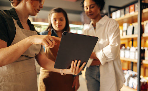 Grocery store manager using a digital tablet with her employees