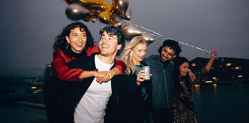Cheerful friends enjoying a night out by the water with balloons