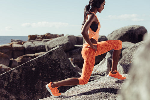 Female runner stretching legs on rocks