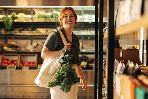Happy young woman grocery shopping in a supermarket