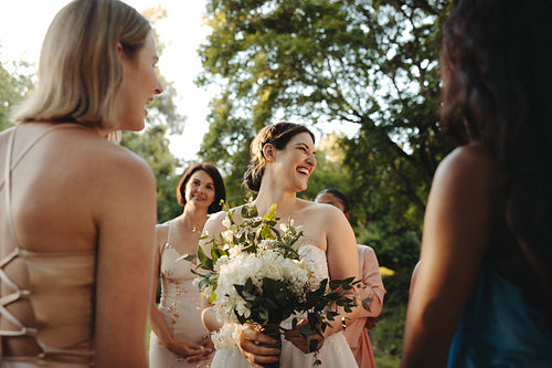 Bride smiling surrounded by bridesmaids in an outdoor wedding setting