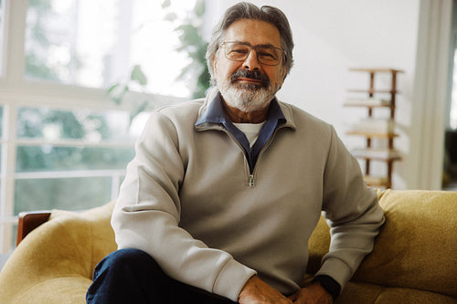 Senior man sits at home on a sofa in retirement