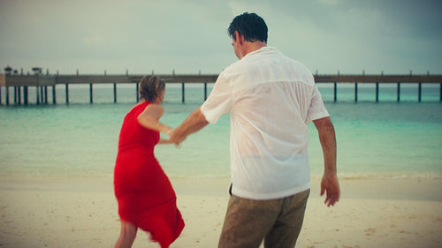 Happy couple enjoys playful vacation running and splashing in the tropical ocean water