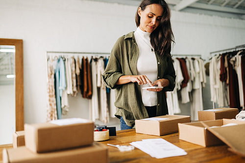 Business woman processing a package for dropshipping using a mobile scanner app