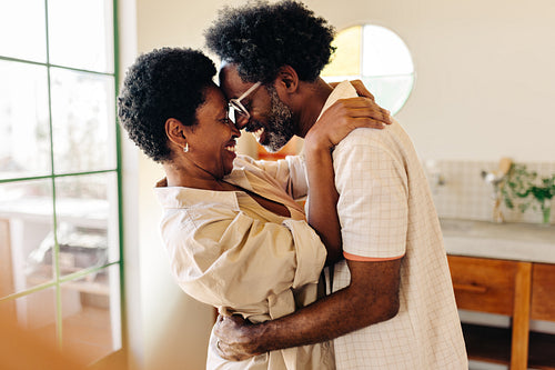 Smiling afro-brazilian couple embracing in kitchen