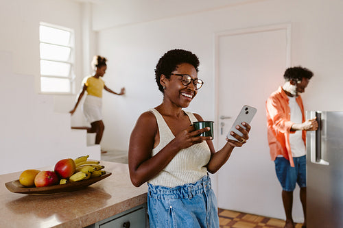 Happy black mom using a mobile phone in the kitchen at home
