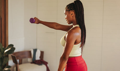 Woman working out with dumbbells in home gym