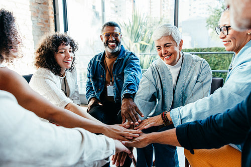 Diverse team joining hands in a positive and happy office setting