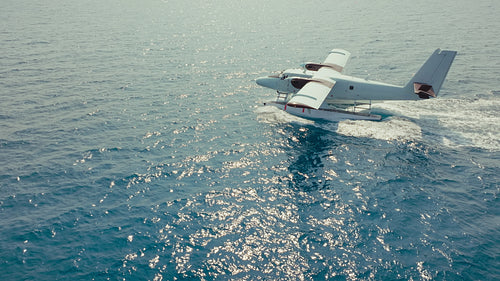 Seaplane arriving at a luxurious tropical island resort with overwater bungalows on clear blue water