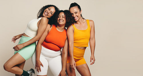 Female fitness friends smiling and standing together in sportswear