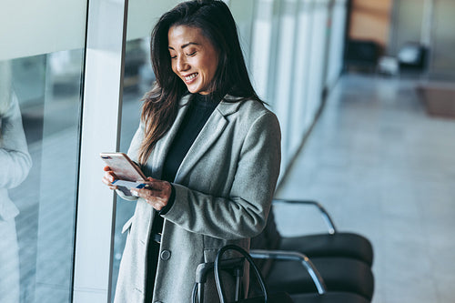 Woman waiting at airport lounge using phone