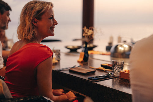 Smiling woman enjoys fine dining experience at sunset with friends