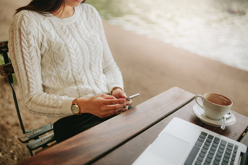 Young woman sitting at outdoor cafe using cellphone