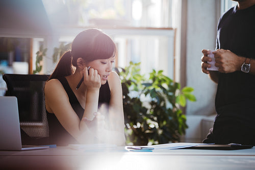 Woman at her desk and talking with male colleague