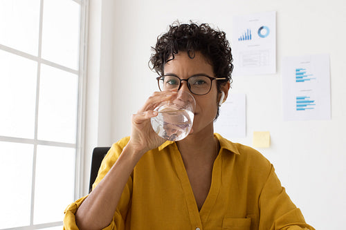 Professional woman drinking water in a video conference