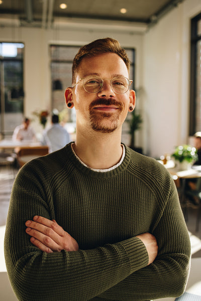 Happy manager looking at camera and standing in office space