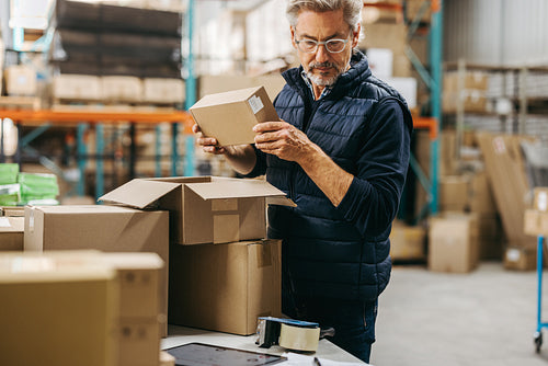Mature man packing orders in a warehouse