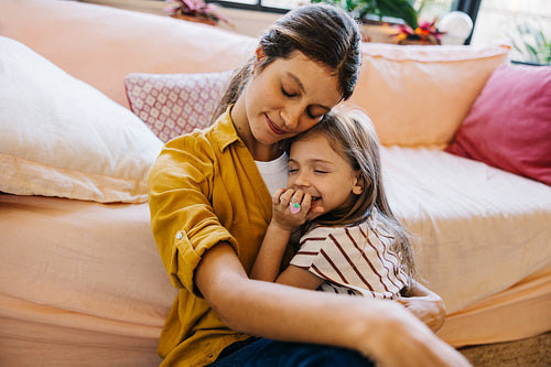 Mother and daughter cuddle on living room couch