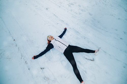 Woman relaxing in snow after winter run for playful seasonal recreation