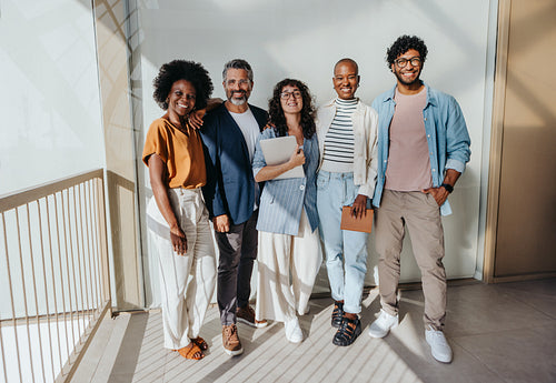 Diverse group of business professionals smiling and standing in modern office