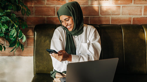 Businesswoman with a hijab using a smartphone in a cafe