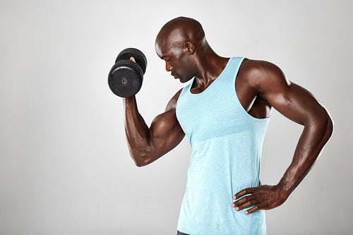 Young muscular man doing heavy dumbbell exercise