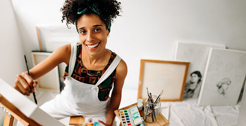 Happy art painter drawing on a canvas in her art studio