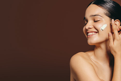 Woman indulging in a skincare routine, she gently rubs an exfoliating cream on her face