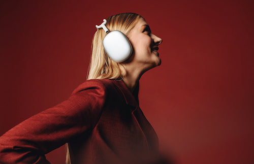 Young woman in red suit enjoying music with over-ear headphones