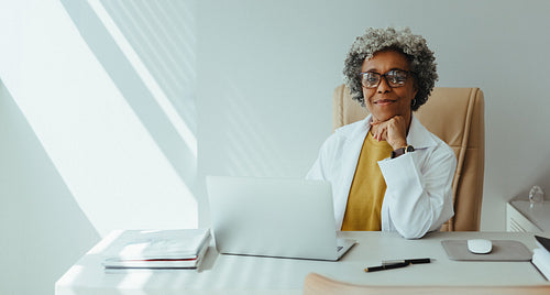 Senior female dentist working with laptop at office desk