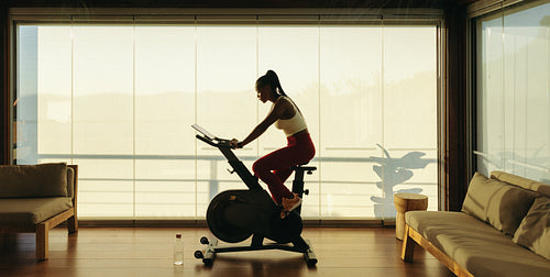 Exercise bike workout: Young woman training in virtual fitness class