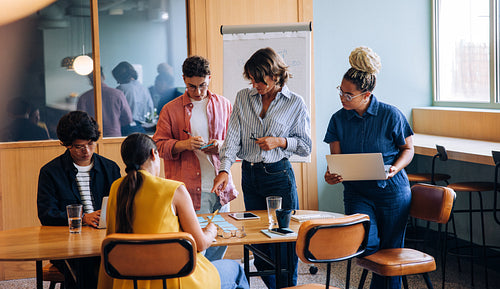 Group of colleagues discussing a project around a wooden table