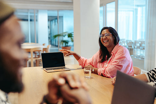 Smiling Indian businesswoman in a bright office sharing ideas during a team meeting