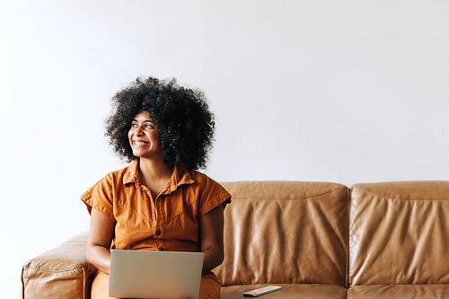 Thoughtful black businesswoman smiling while working on a laptop