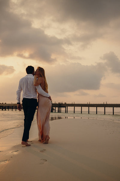 Romantic walk on the beach at sunset capturing a kiss during a luxury vacation