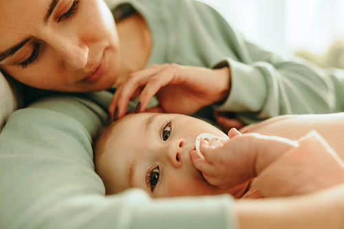 Mother cuddling her baby on the bed
