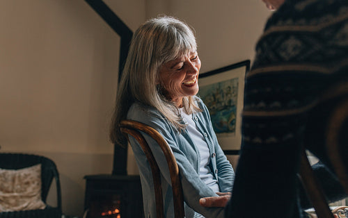 Senior woman sitting on chair at home and laughing