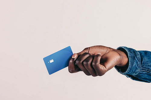 Tap to pay: Man's hand holding out a credit card in order to make a payment in a studio