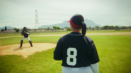 Female baseball pitcher throws to catcher on the field