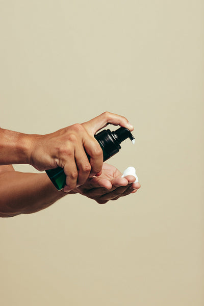 Young man dispensing a facial cleanser on his fingers, preparing for a face wash