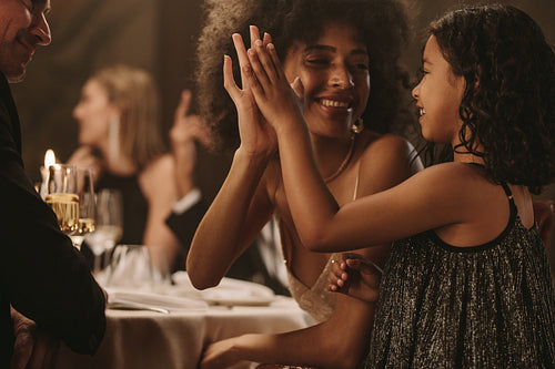 Girl having fun with her mother at gala party