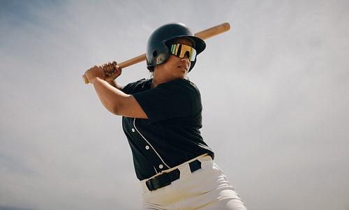 Confident baseball player prepared to swing as batter at home plate during daytime game
