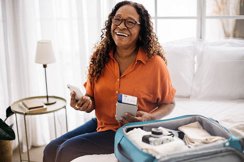 Mature female traveler using a mobile app to pack for an international trip