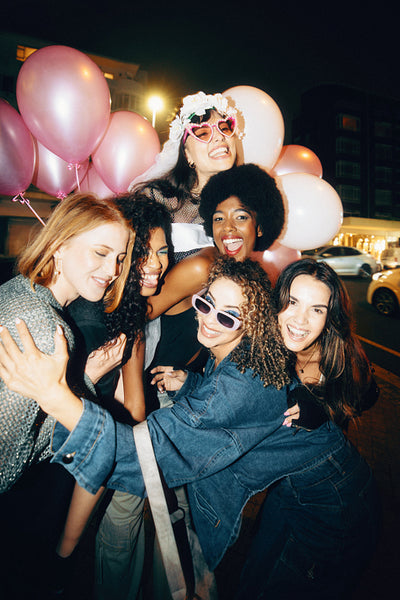 Group of happy women enjoying a midnight celebration with balloons outdoors