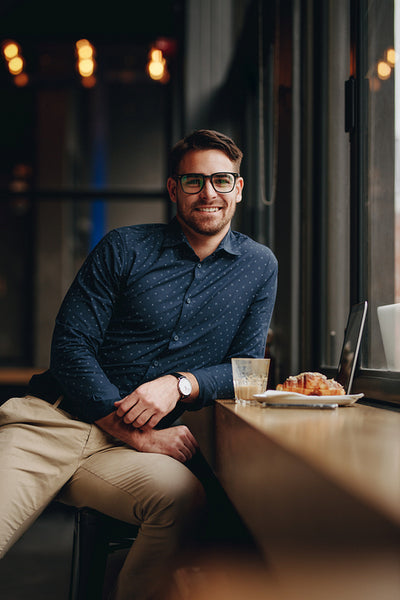 Smiling man sitting in restaurant with food and laptop on table