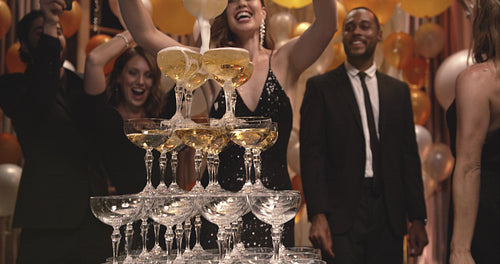 Beautiful woman pouring champagne in the pyramid of glasses at party
