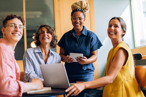 Smiling coworkers in a meeting with laptops and digital devices