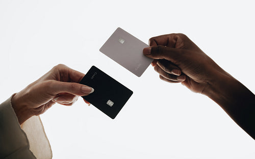 Two hands holding credit cards in a minimal close-up composition