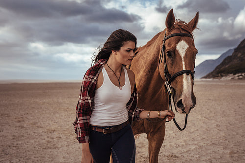 Woman walking with horse on the coast